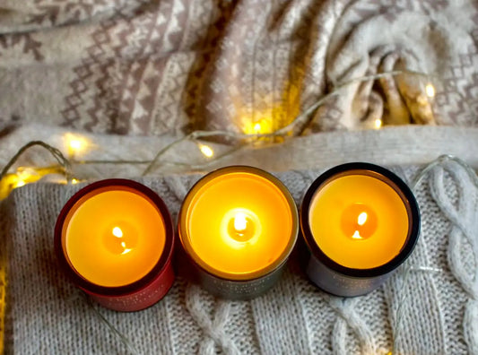 glowing beeswax candles on winter sweater with cozy string lights