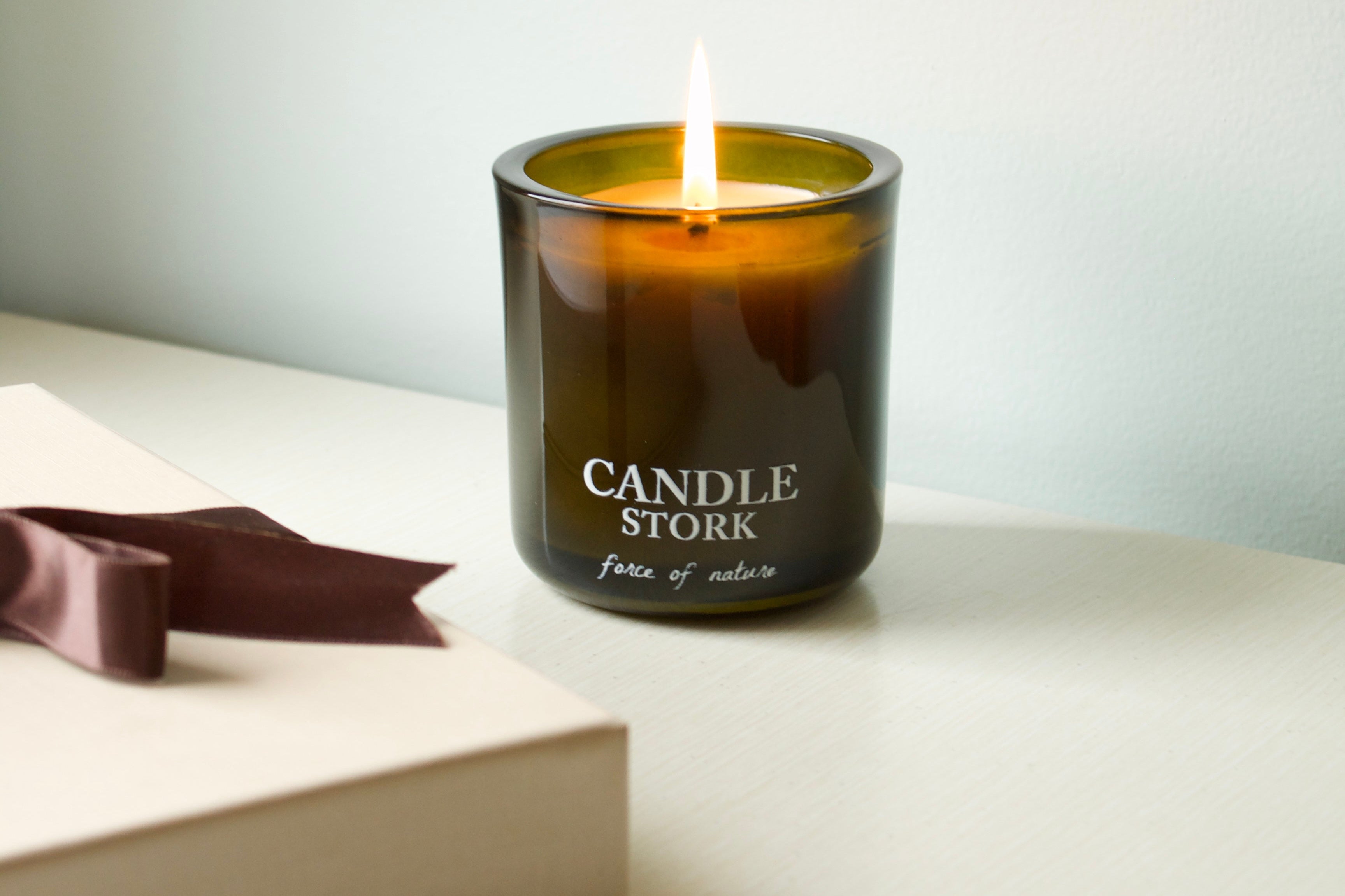 Candle Stork candle on a white surface with a book and ribbon