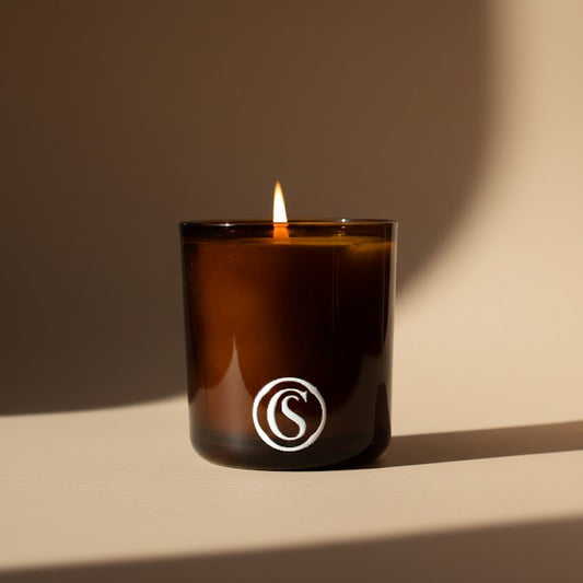 Candle in an amber glass with a logo on a beige background