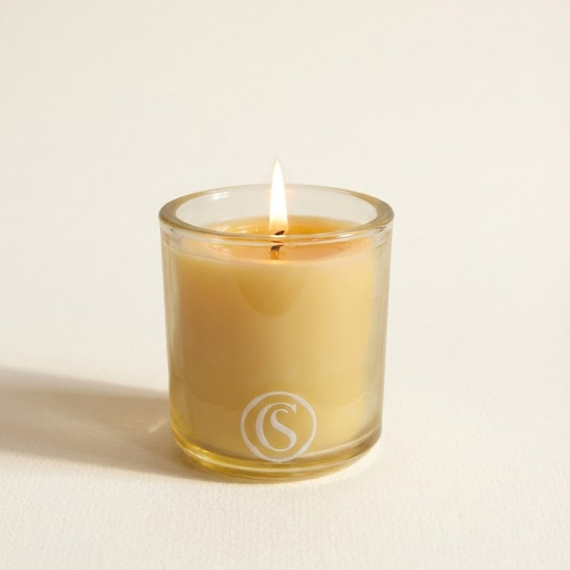 Glass candle with a logo on a light beige background